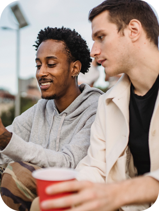 Two young men talking outdoors while holding a red cup