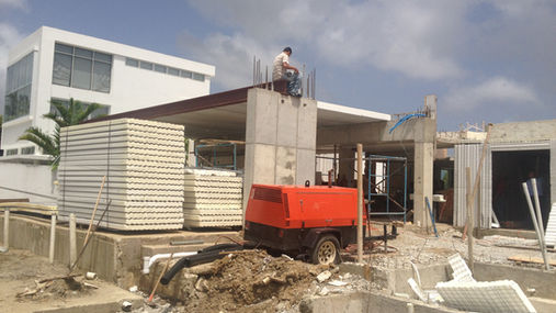 Construction site with workers and machinery, modern white building in background