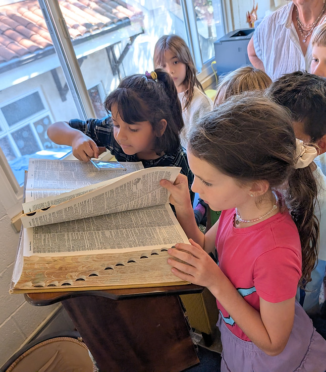 Third grade students reading together from a dictionary