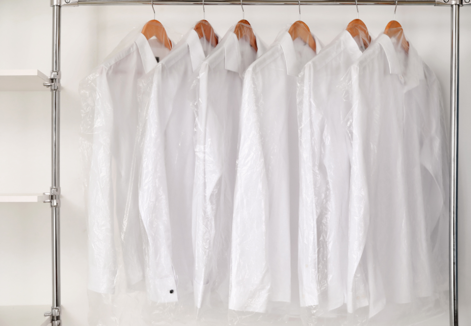 White shirts on hangers in a wardrobe with clear plastic covers