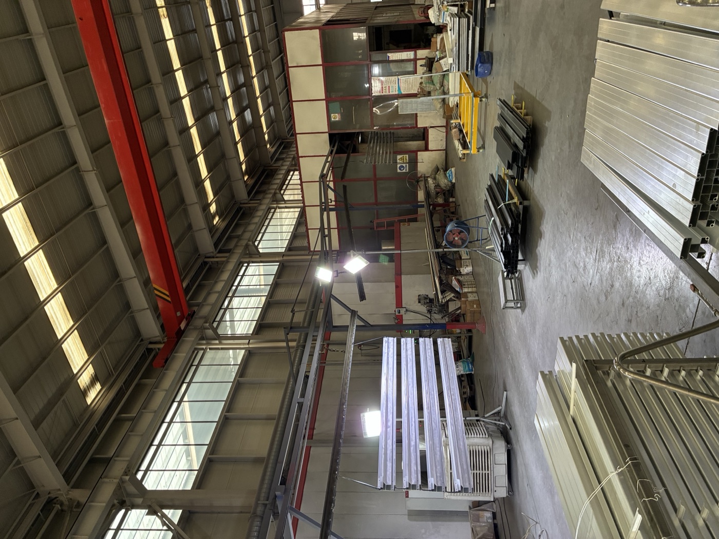 The factory floor with aluminum profiles laid out under an overhead crane