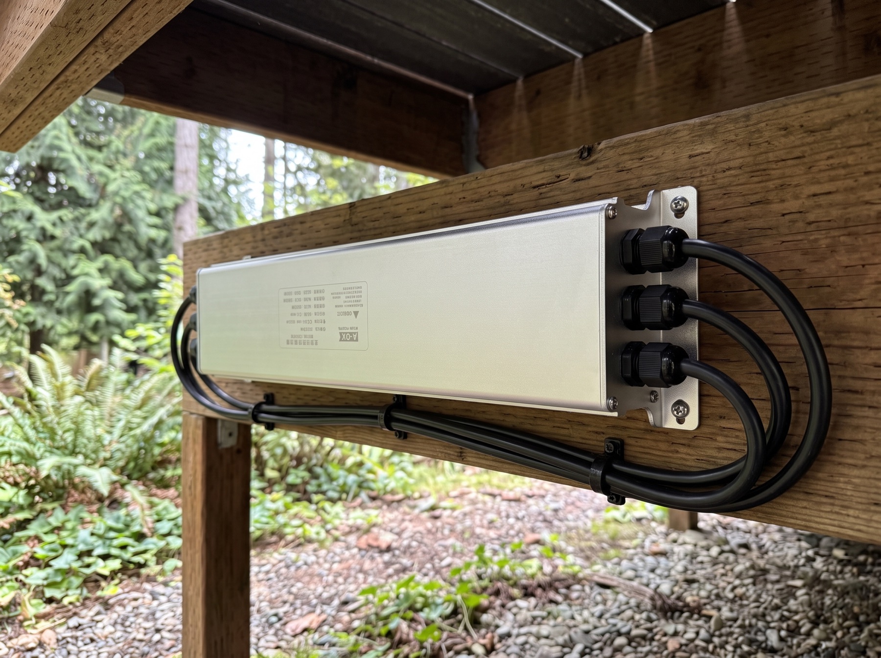 The Series II aluminum controller box screwed to a wood joist under a backyard deck, with its sealed cables clipped neatly along the beam