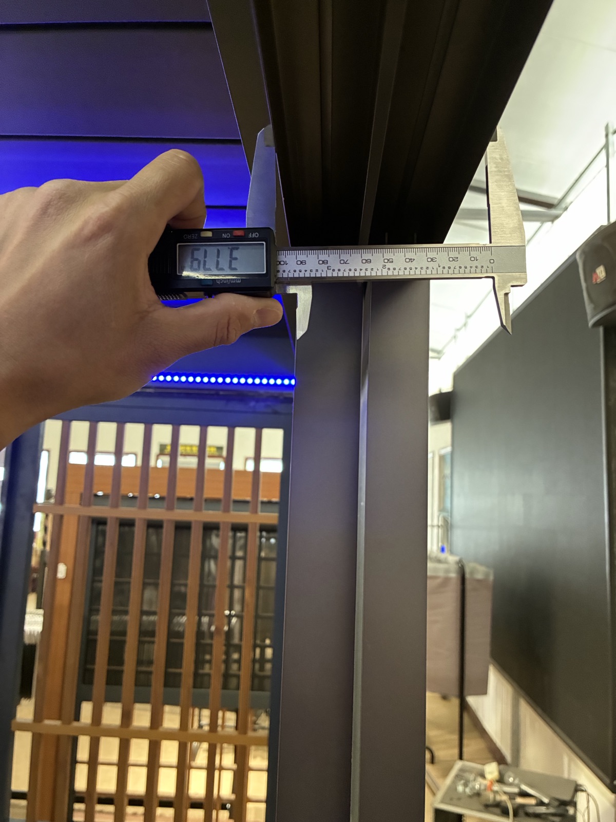 A caliper measuring a finished pergola post in the showroom