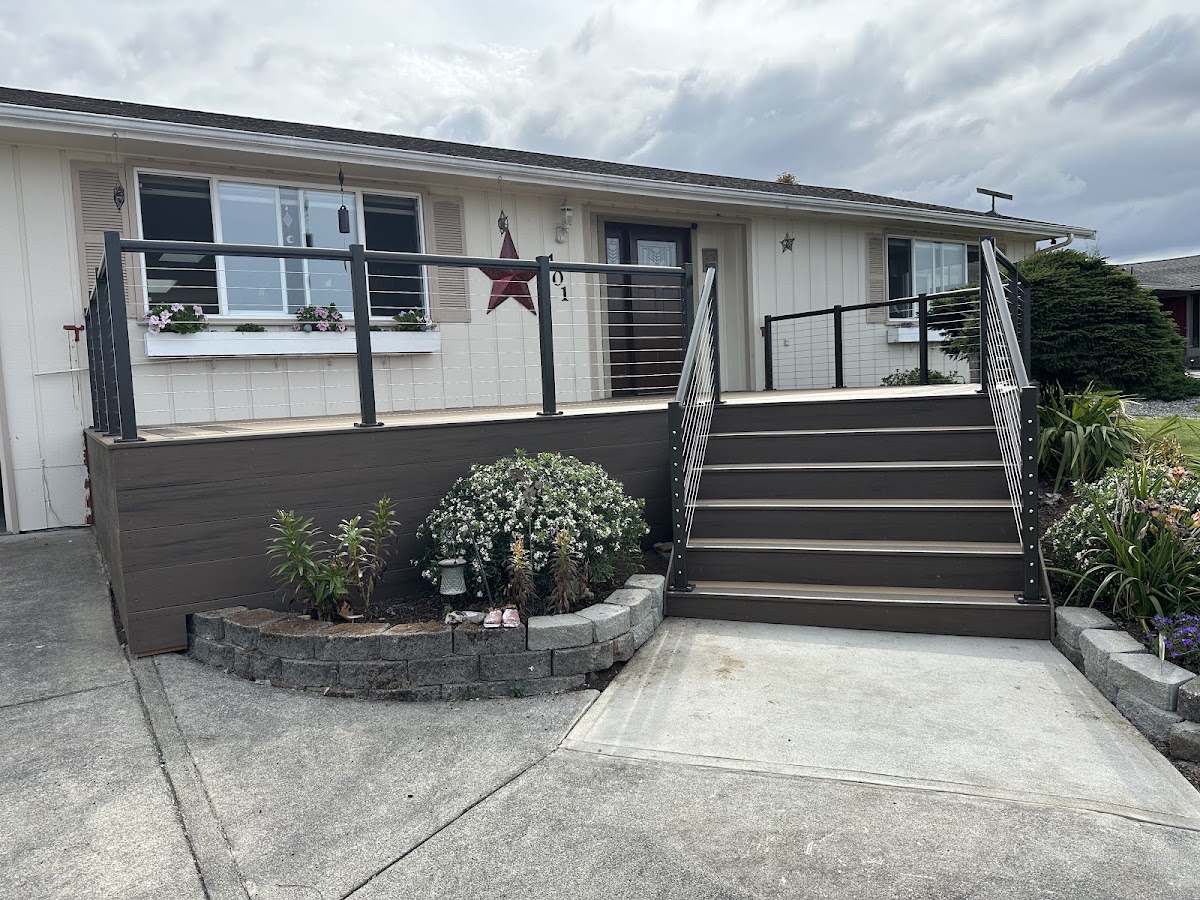 A composite front deck with steps and cable railing built by Heartwood Home Exteriors