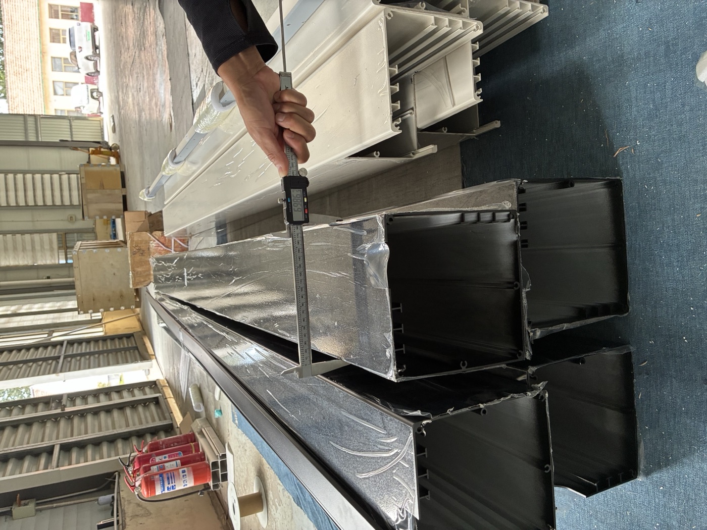Black and white aluminum profiles stacked on the factory floor