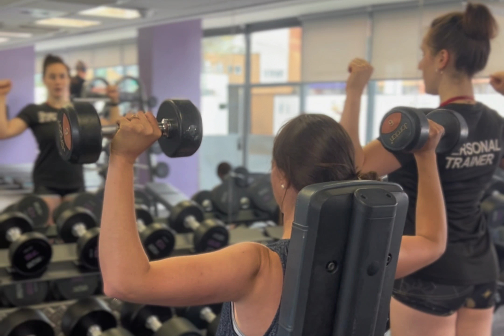 Eye-level view of a woman lifting weights in a bright gym