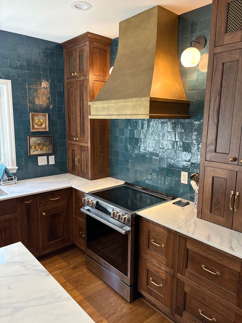 Kitchen with blue tile, brass oven hood, dark wood cabinets and white quartz countertops