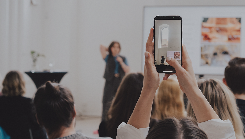Person filming a speaker at a presentation