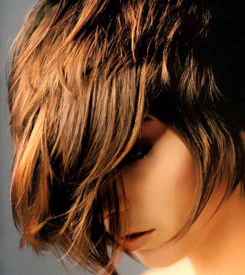 Woman with short, layered hair, partially covering her face About AlbertColor, top hair salon in nyc