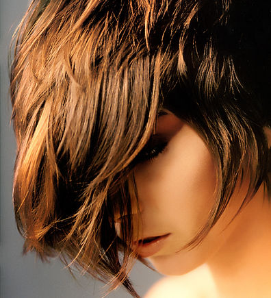 A woman with short brown hair poses with a friendly expression, showcasing her casual style in a bright setting.