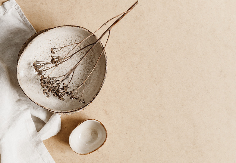 Minimalist ceramic bowl with dry plant over kraft paper background. Copy space, flat lay..