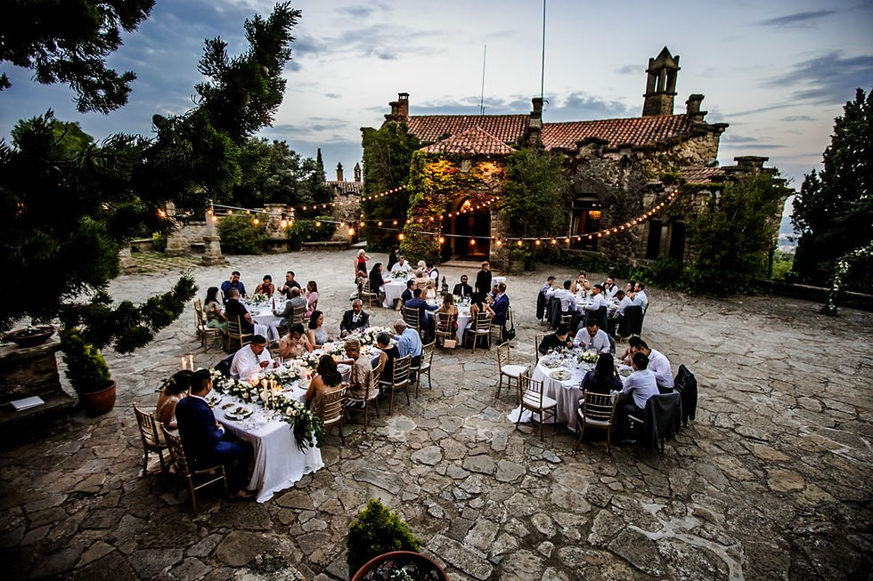 Wedding guests enjoying an outdoor cocktail reception on the stone patio of La Baronia, showcasing the grand historic facade and elegant garden atmosphere.