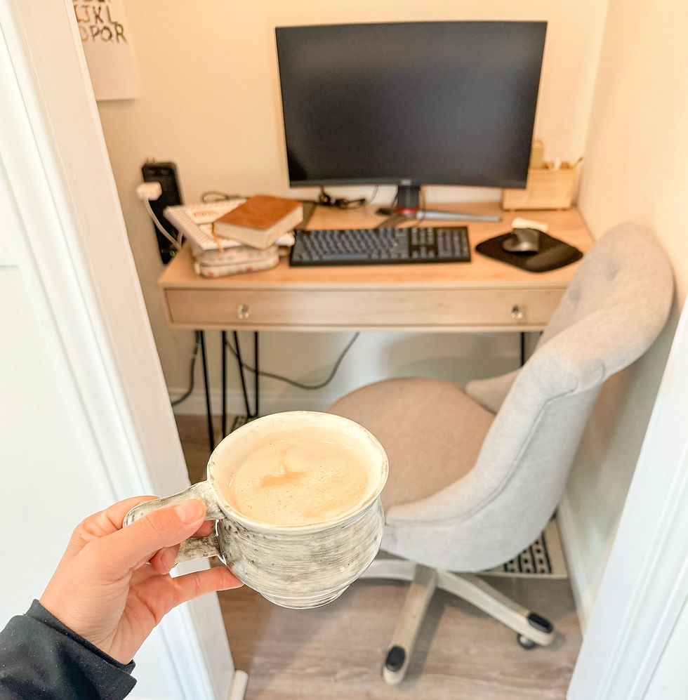 desk with computer as backgroun, and a cup of coffee in focus