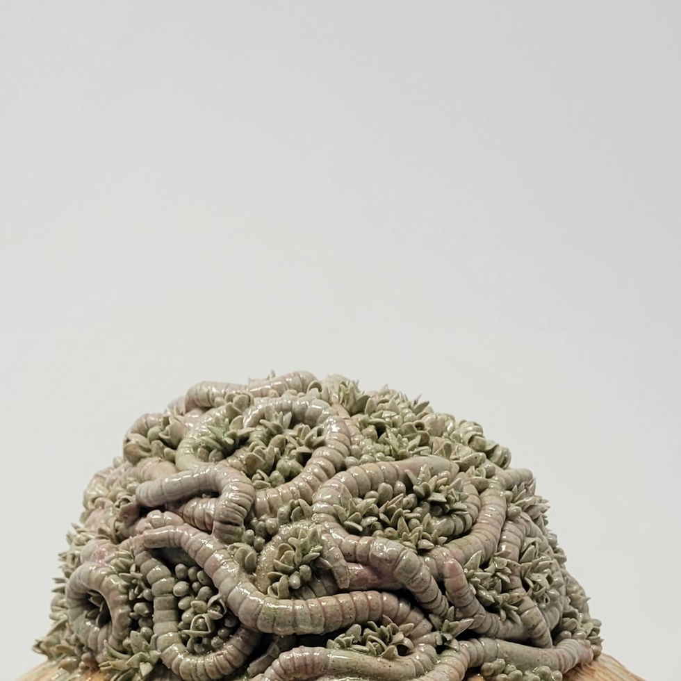 A close up of a ceramic sculpture of worms in moss.