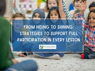 A group of children sit on the floor in front of a teacher with hands raised and smiles on their faces eager to answer.