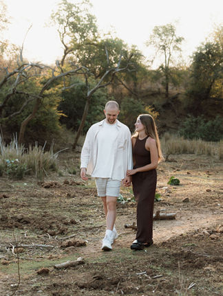 Couple walking hand in hand through the bush veld after safari proposal
