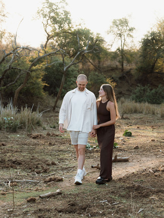 Couple walking hand in hand through the bush veld after safari proposal