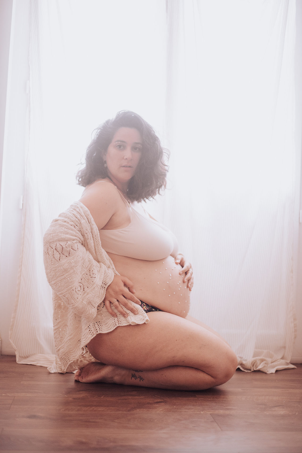Portrait de grossesse en lumière naturelle mettant en valeur la maternité et la douceur.