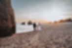 Traumfoto beim Sonnenuntergang in Portugal an der Küste. Sie haben gerade am Strand geheiretet und genießen den Sonnenuntergang.Tätowierte Braut im Spitzenhochzeitskleid – Hochzeitsfotograf & Videograf Mason Photography aus Düsseldorf.