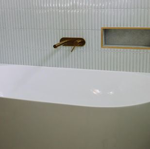 White bathtub with gold faucet in a modern bathroom setting