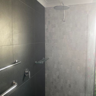 Modern bathroom with a large shower head, towel racks, and glass walls.