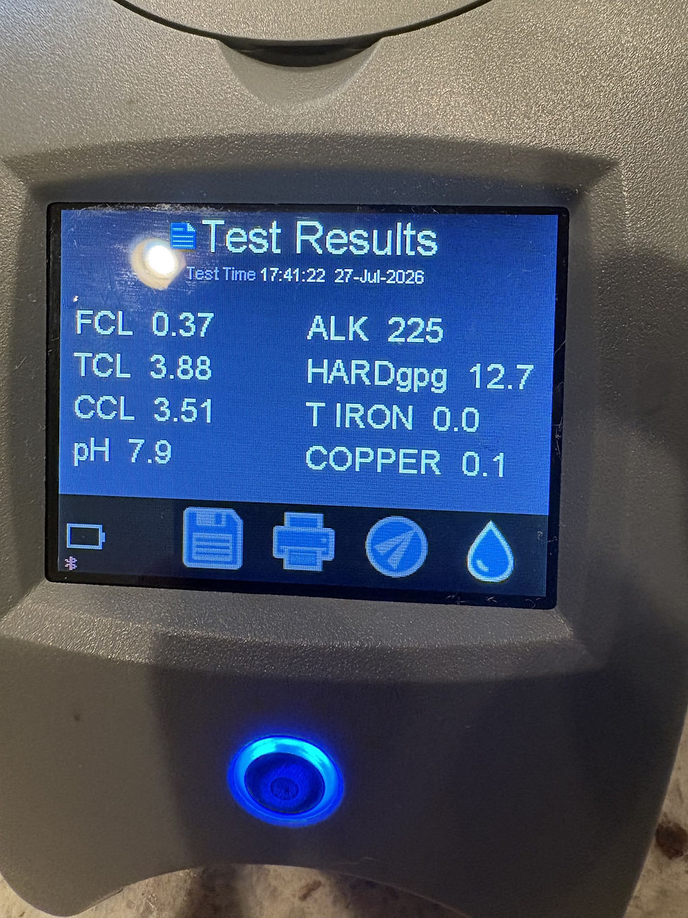 A water test meter screen showing hardness, iron and chlorine results in grains per gallon and ppm
