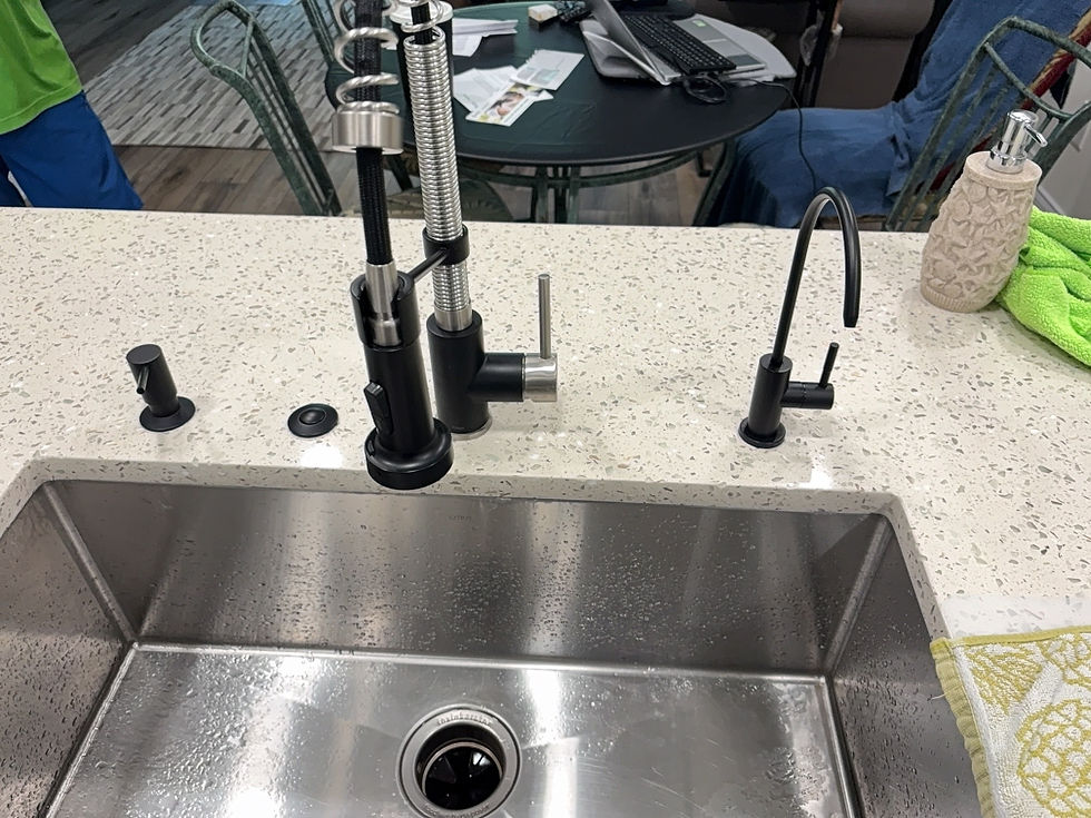 Black reverse osmosis faucet beside a pull-down kitchen faucet on a quartz counter