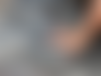 A hand rests in a large dinosaur footprint fossil on textured, brown rock.