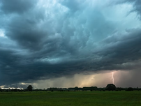 Stormy sky over a green field, dark clouds with a bolt of lightning striking in the distance. The mood is dramatic and intense.