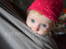 Baby wearing a red hat in a carrier
