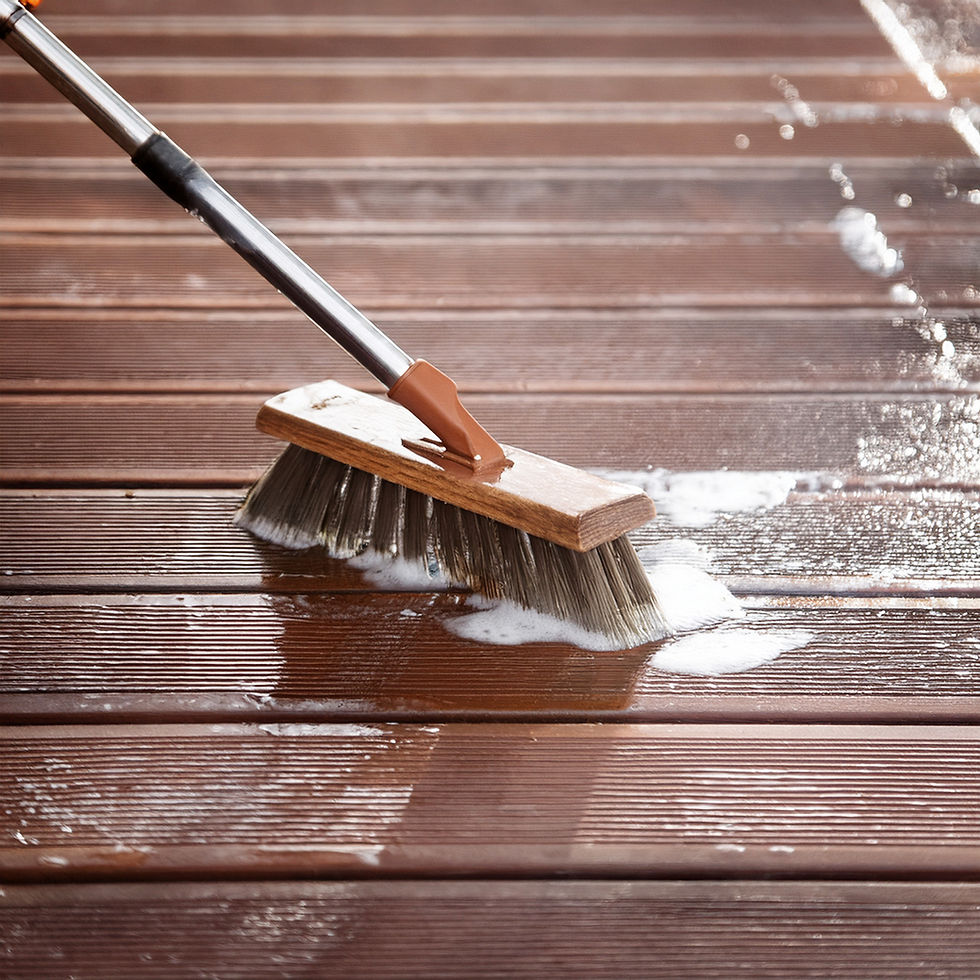 Brush scrubbing a wooden deck with soap suds. The deck is wet, with brown planks. No visible text or people, just cleaning action.