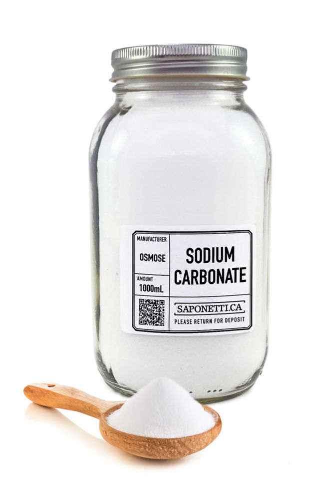 A glass jar labeled "Sodium Carbonate" with a metal lid is filled with white powder. A wooden spoon with white powder is in front.
