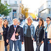 Groupe de femmes souriantes se tenant ensemble dans une rue piétonne, lumineuse.