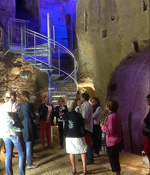 Groupe de personnes visitant un escalier en colimaçon dans un château historique.
