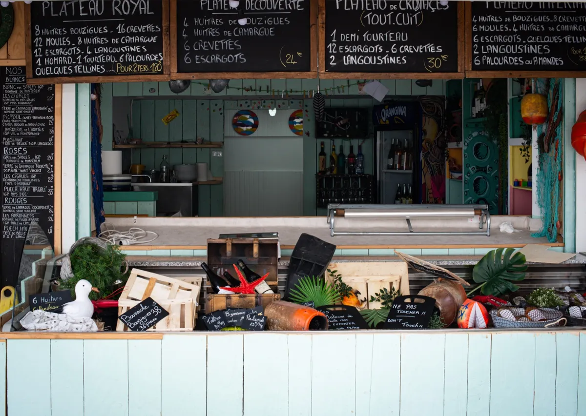 Nadmorska restauracja z tablicą pełną owoców morza – Urocza nadmorska knajpka serwująca świeże owoce morza i tradycyjne dania, charakterystyczna dla wybrzeża Camargue.