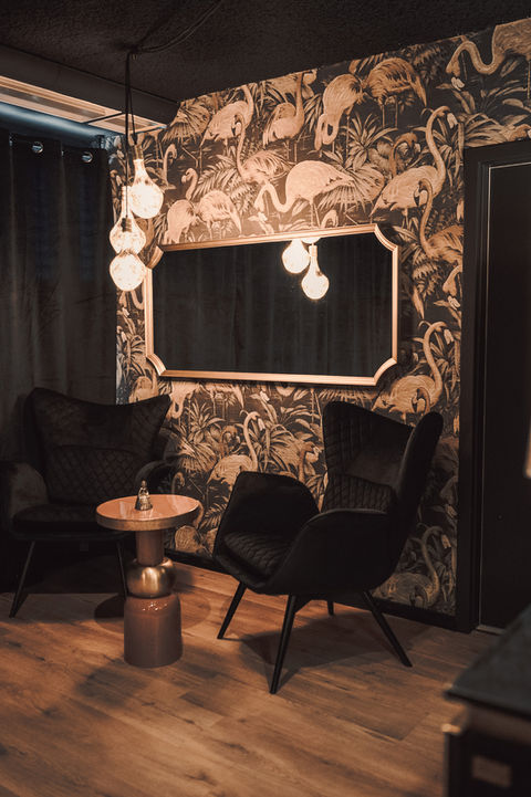 Two black armchairs and mirror with flamingo wallpaper background VC-Studios