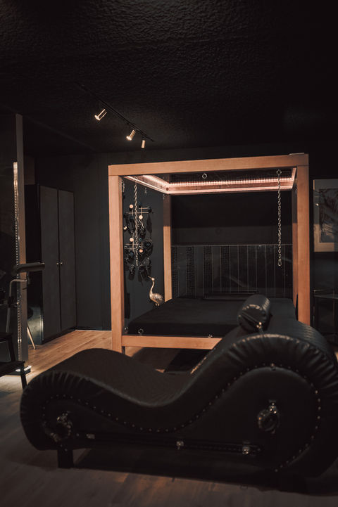 Black leather couch and wooden bed frame. VC-Studios and BDSM Mietstudio Zürich.