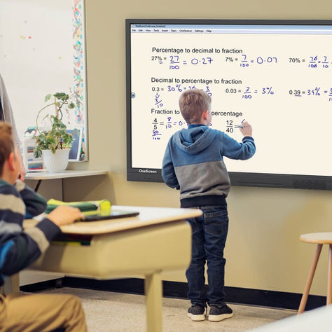 Un maestro y dos niños observan una pizarra digital en un aula en Guatemala.