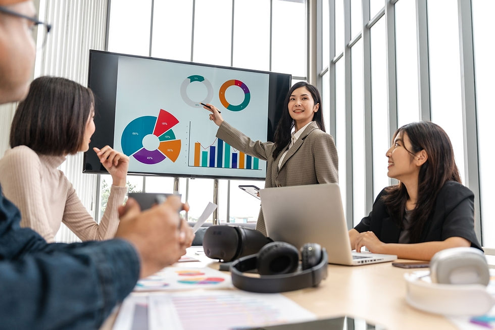 Mujer de negocios asiática presenta gráficos en una pizarra digital durante una reunión.
