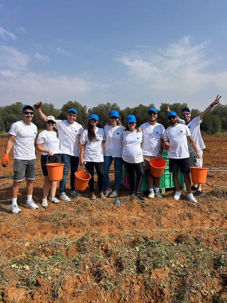 Team members in white shirts holding buckets in a field