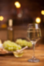 Glass of white wine on table with grapes and honey.