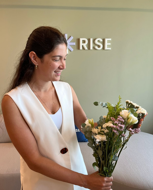 Woman smiling, holding flowers, with RISE logo