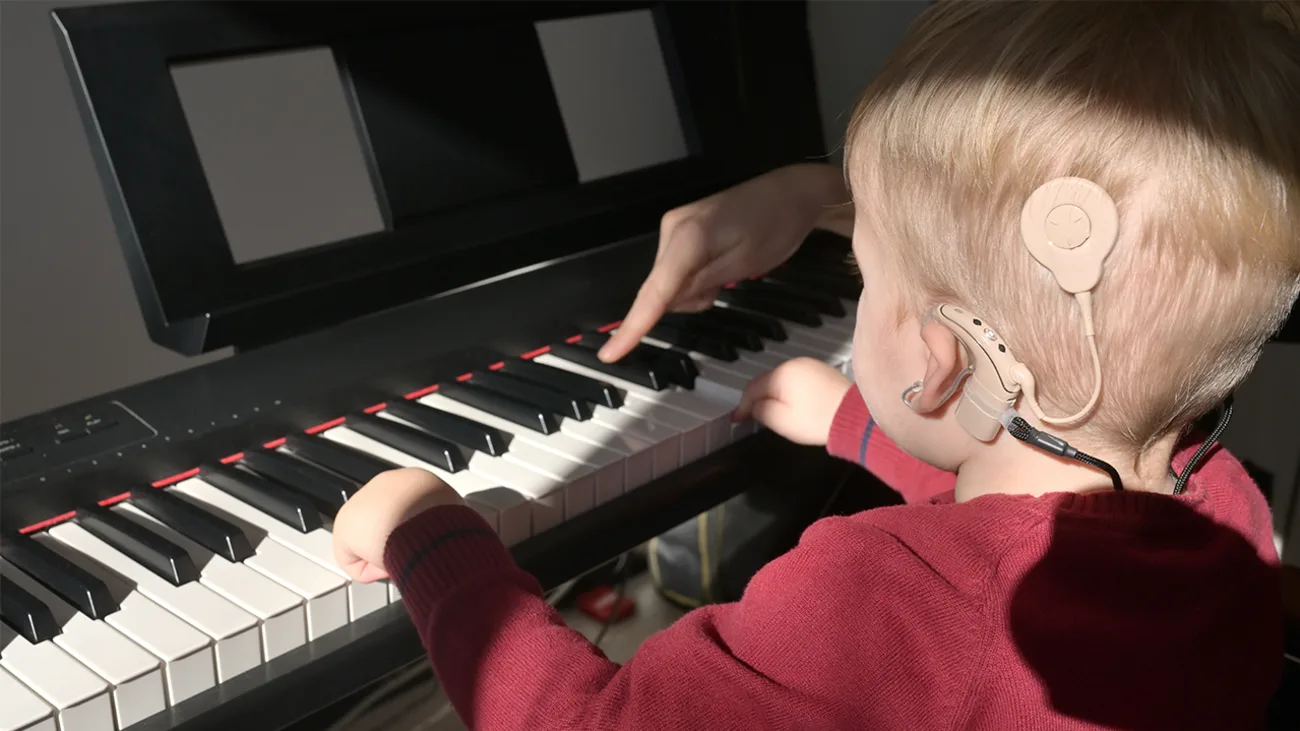 a child with cochlear implant learning to play on piano