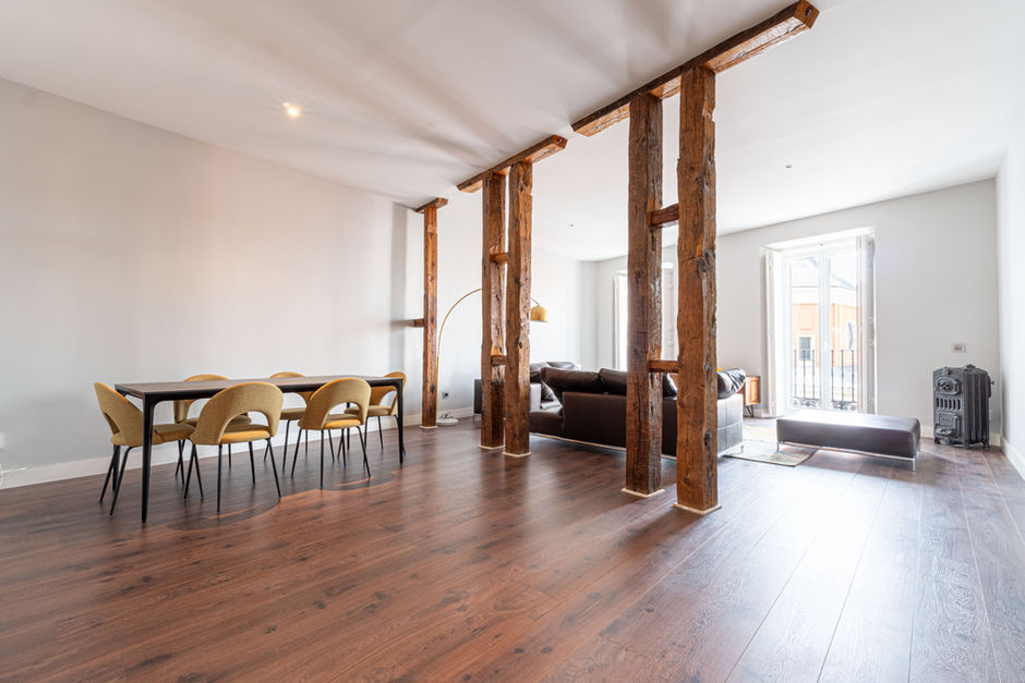 Comedor con vigas de madera, suelo de parquet y luz natural – fotografía profesional de interiores en Madrid.