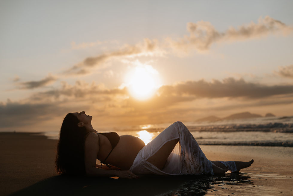 Grávida no nascer do sol na praia em Macaé