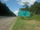 Uma placa de beira de estrada indicando distância e nomes de cidades