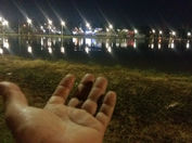 uma mão apresentando um lago e muitas luzes refletidas nele