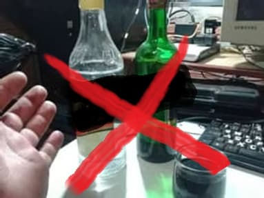 Mão próxima à garrafas sinalizadas para não beber