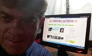 Humano servo de Deus em frente de uma tela de computador onde está exibido o site Eu Preciso de Deus