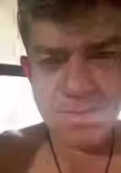 Um homem sem camisa olhando seriamente para a câmera